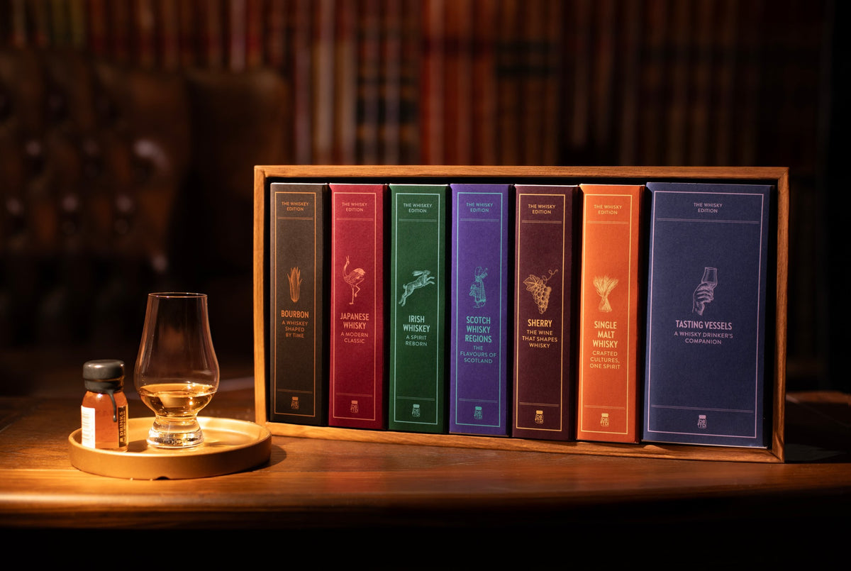 The Dramthology Bookshelf: seven whisky books on a wooden shelf